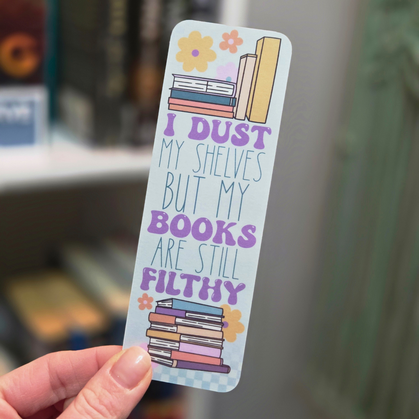 Bookmark with text and book illustrations held by a hand in an indoor setting